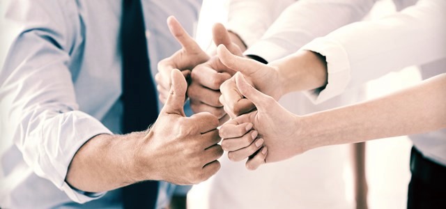 equipe com as mãos unidas e fazendo sinal de positivo