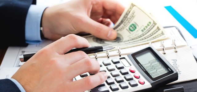 mãos mexendo em calculadora e dinheiro
