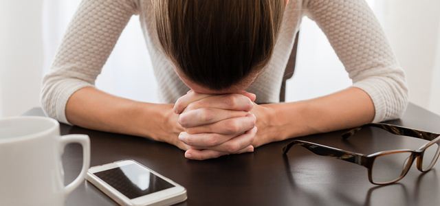 mulher preocupada com a cabeça apoiada na mesa