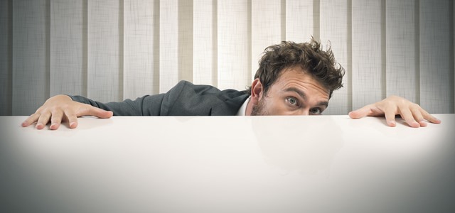 homem se escondendo atrás de mesa