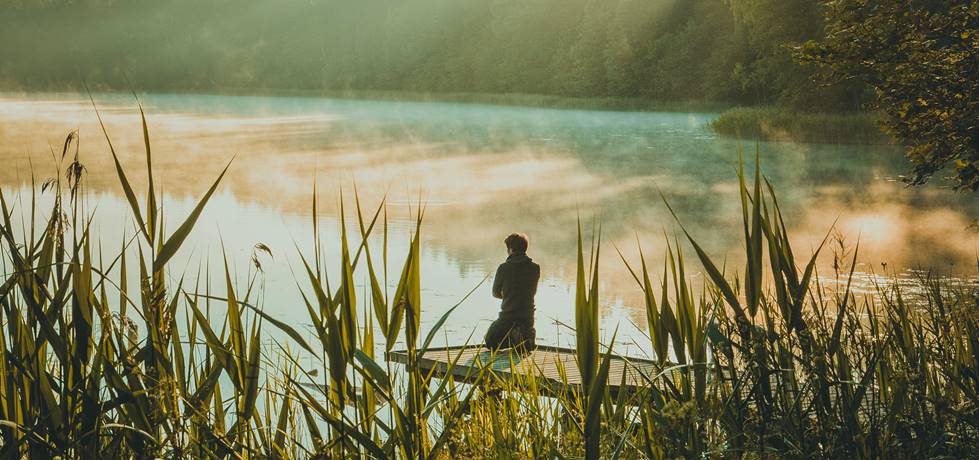 homem meditando a beira do lago