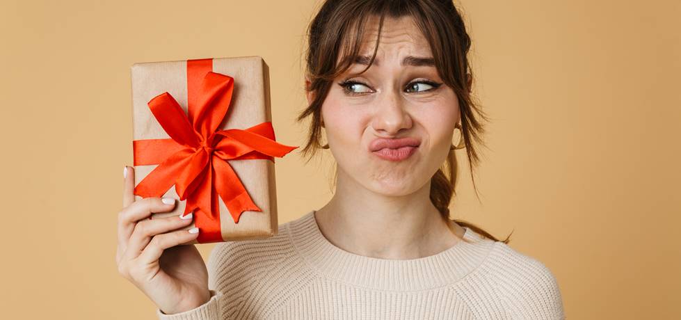 Mulher fazendo uma cara de insatisfeita enquanto segura um presente